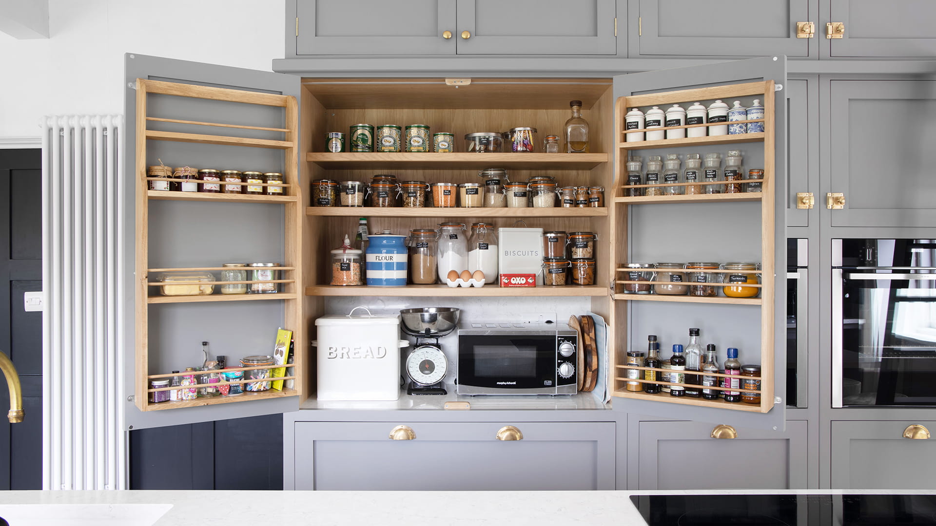 Open cupboard with various spices and baking equipment inside